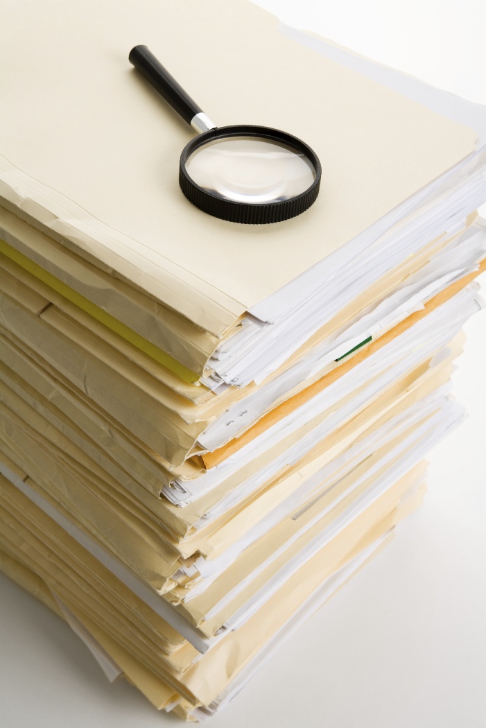 A magnifying glass positioned atop a stack of papers